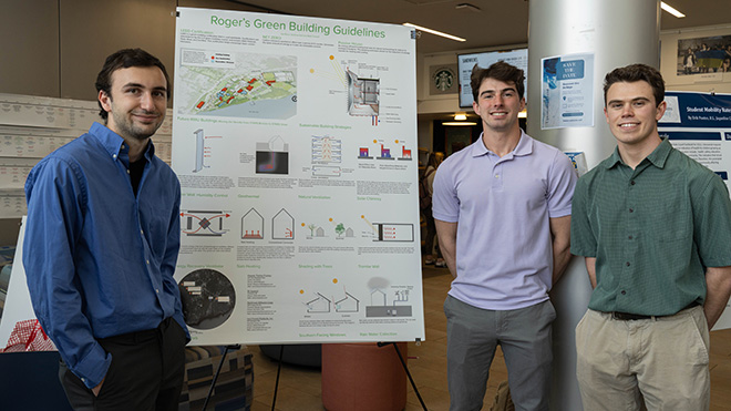 Three Architecture majors stand with their poster at SASH