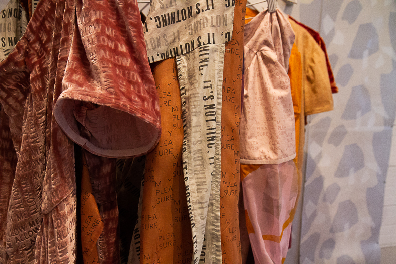 Garments with printed text hanging on rack.
