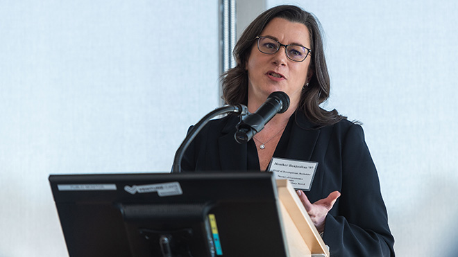 Heather Boujoulian speaking into a microphone at a podium