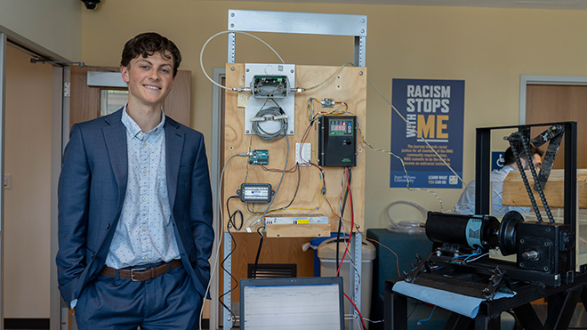 An Engineering student stands next to his SASH project