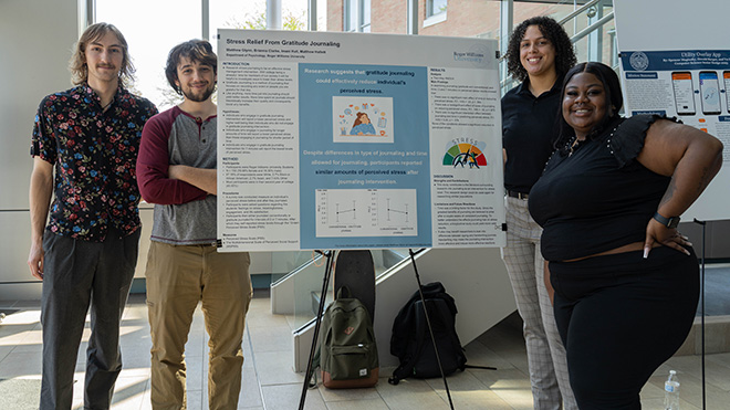 Four Psychology majors standing around their poster.