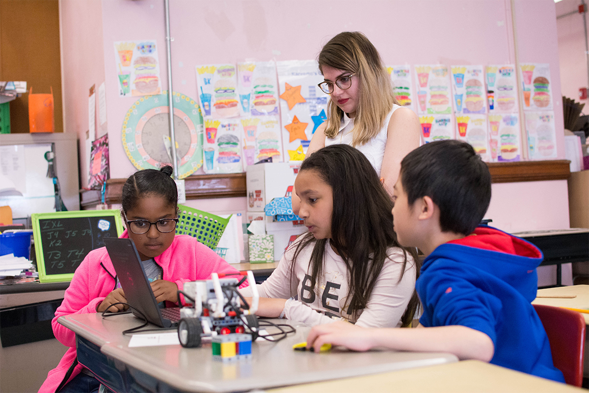 RWU student watchesstudents adjust their programing code-block