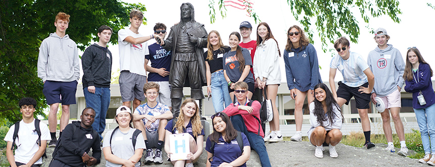 Students pose with Roger Williams statue on campus