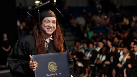 An RWU Extension School graduate celebrates on stage during Commencement ceremonies on May 16.