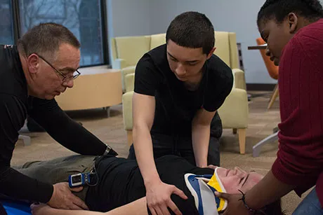 Students at practice placing someone on a stretcher.