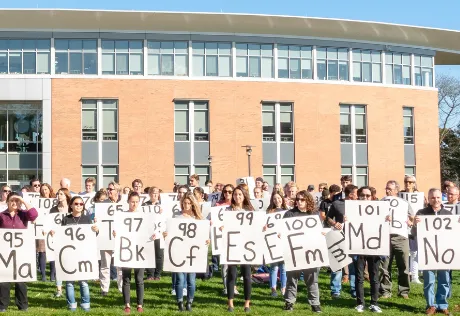 A group of people holding signs for the periodic table of elements.