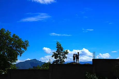 Three children are standing on the roof of a building in the Dominican Republic.