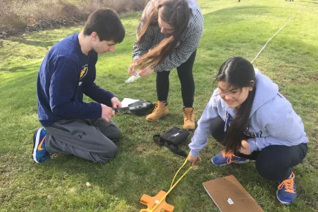 Three students conduct scientific field work.