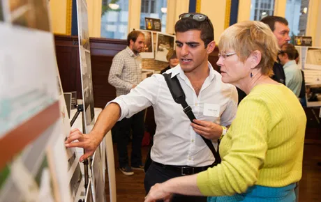 Student explains research poster to a guest
