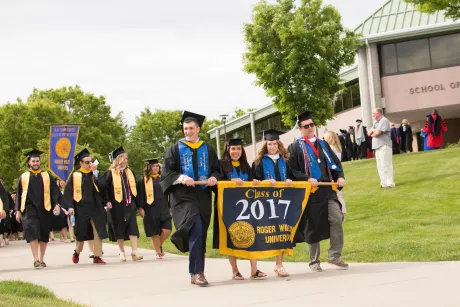 Graduates process to Commencement carrying the class banner.