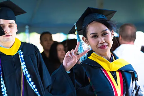 image of Meg Dela Dingco '19 flashing a peace sign at Commencement