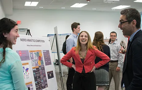 Two students talk about their project with a professor.