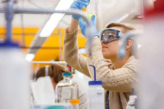 Student looking into beaker.