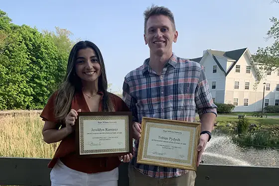 Two ANSOC graduates stand together holding certificates
