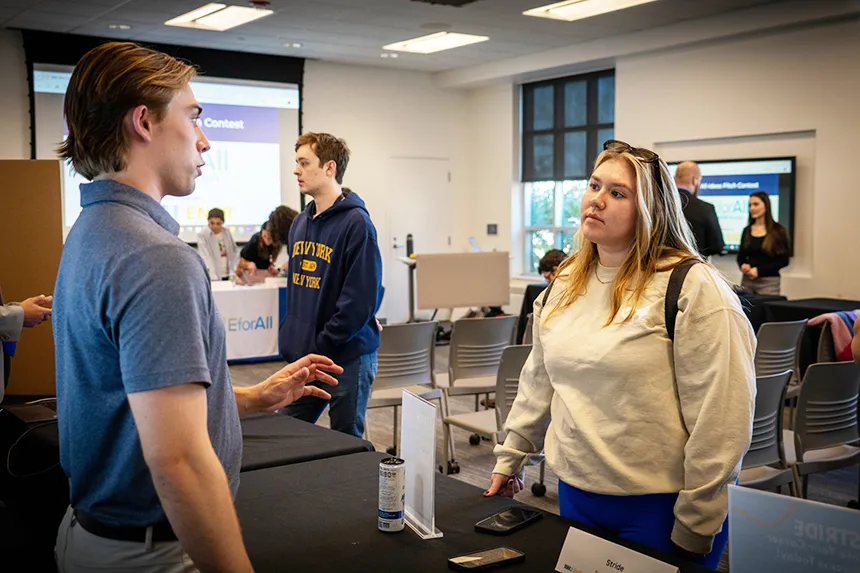 A student entrepreneur speaks to members of the RWU community at her table.