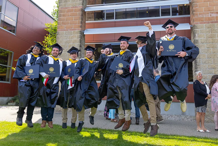 Graduates jump holding degrees