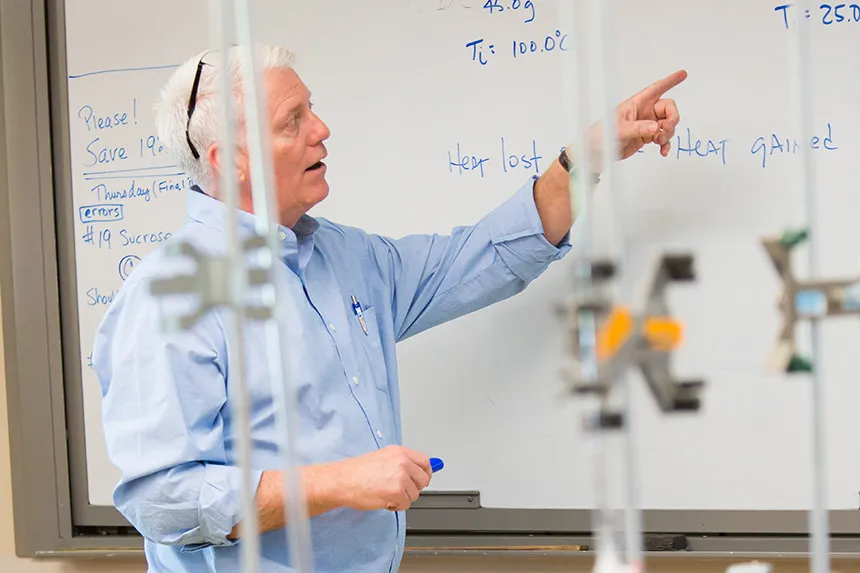 A biology professor pointing to a whiteboard