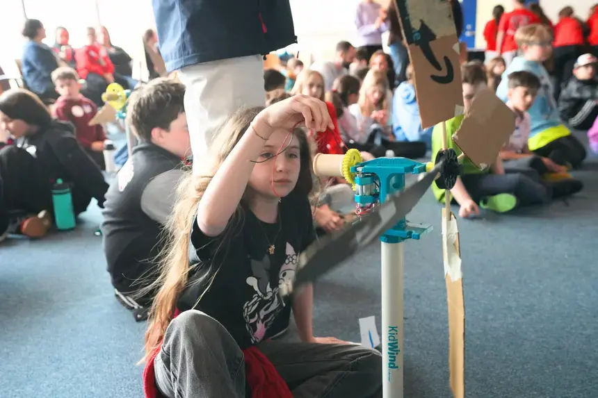 A fourth grader examines her wind turbine.