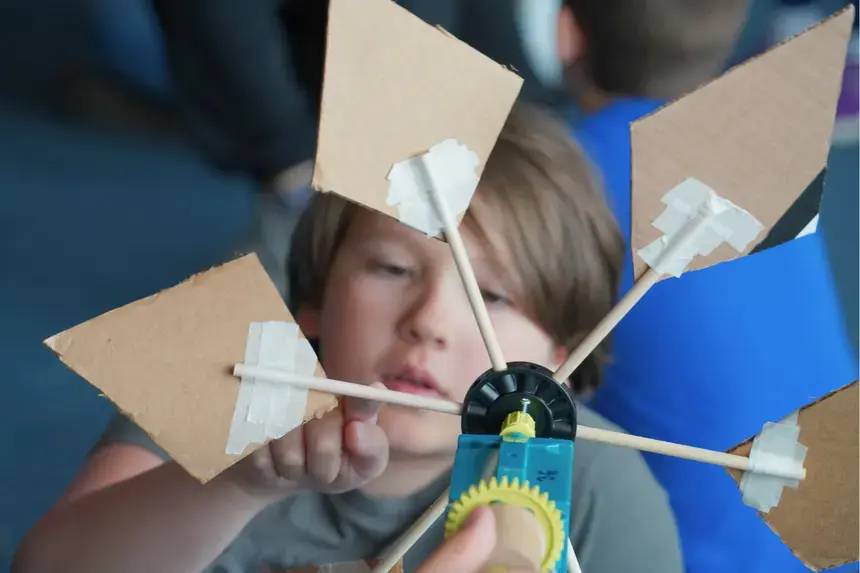 A fourth grader examines his wind turbine.