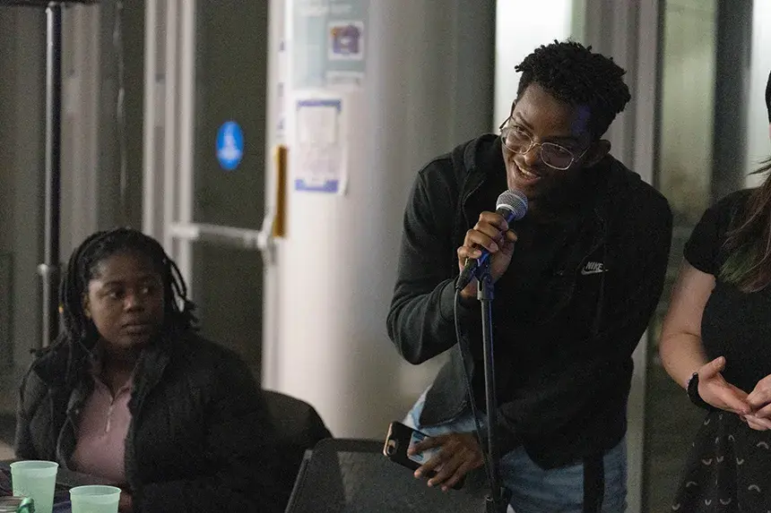 Two MSU officers, one speaking into a microphone and one sitting.