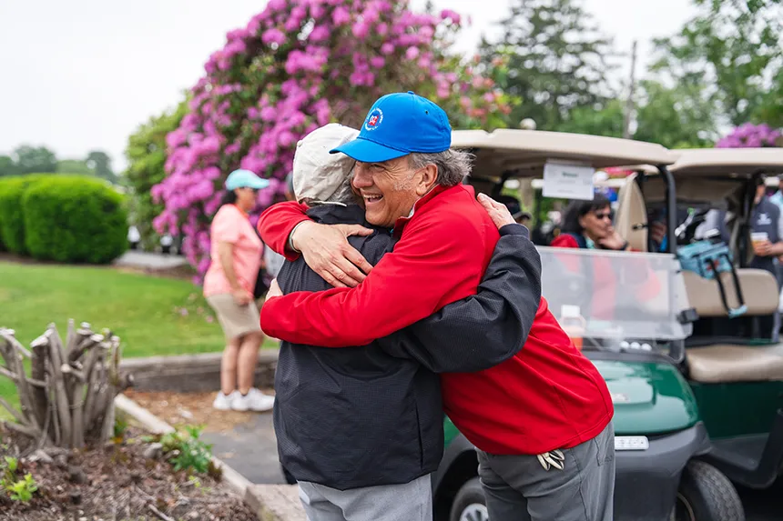 Alumni hug at the start of the 18th Annual Ray Cordeiro Alumni Golf Classic.
