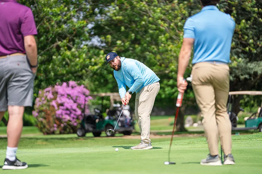 An alum lines up for a chip shot at the 18th Annual Ray Cordeiro Alumni Golf Classic.