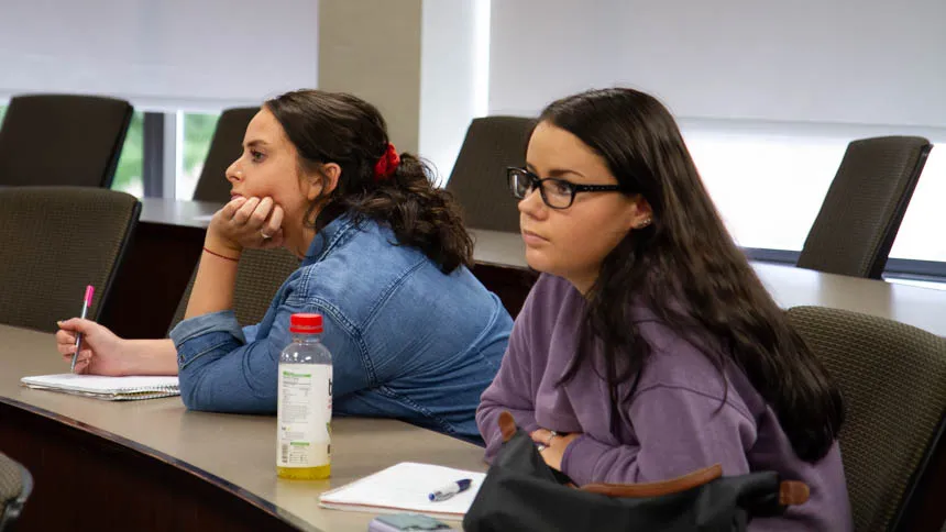 Two students listen to a presentation.