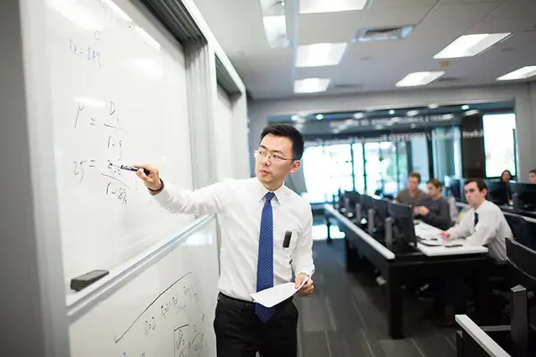 A business professor writing on a whiteboard.